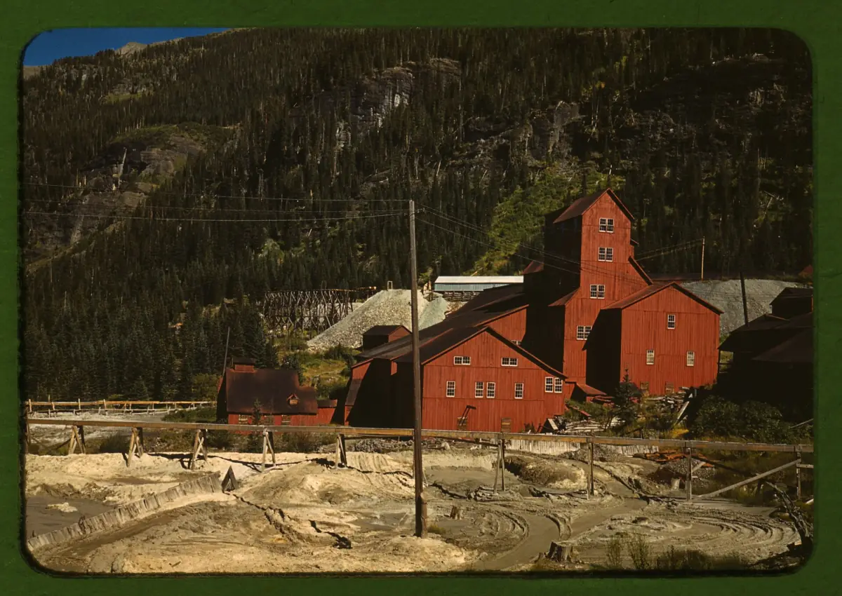 The red wooden buildings of the Camp Bird Mine's mill, with tailings in the foreground, in a color photo by Russell Lee from October 1940.